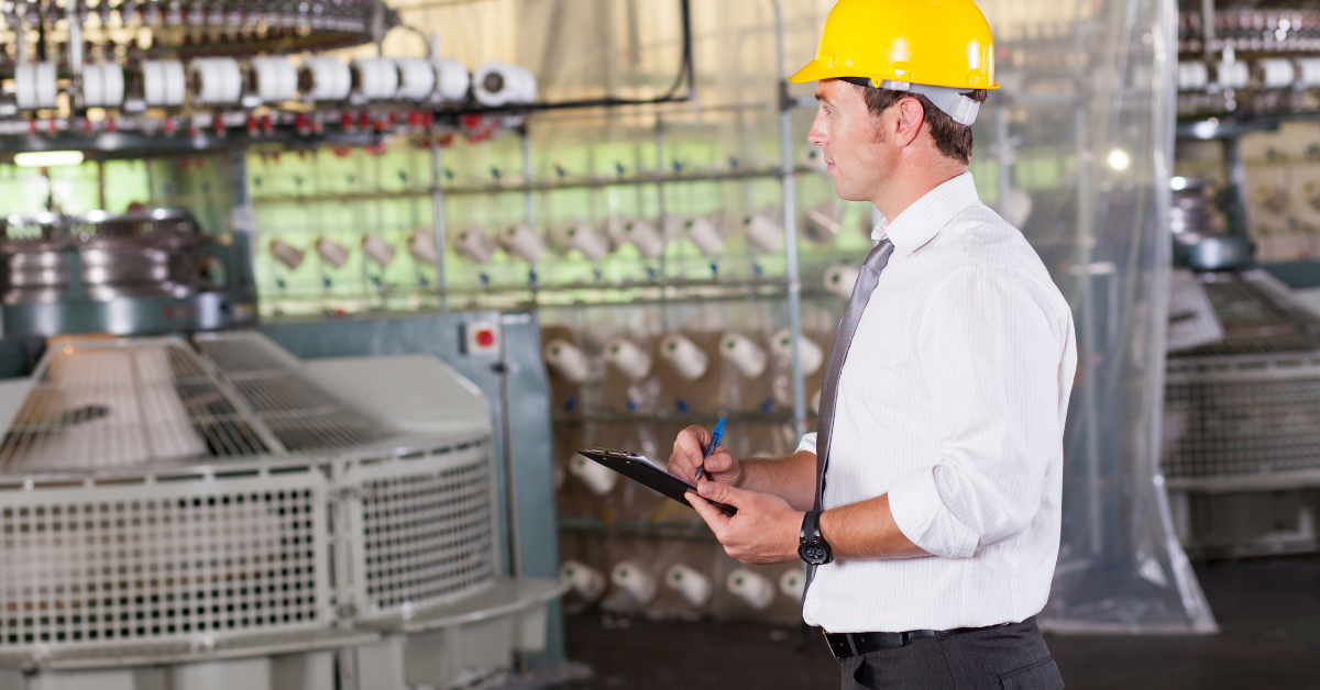 Male manufacturing supervisor with hard hat checking equipment